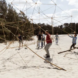 Gezellige workshop bamboetoren bouwen met een groep vrienden in de zon op Scheveningen.