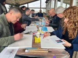 Collega’s genieten van een gezellige workshop schilderen Scheveningen met uitzicht op zee tijdens een creatief bedrijfsuitje