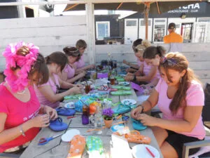 Collega’s versieren kleurrijke slippers tijdens een creatieve workshop slippers pimpen Scheveningen tijdens een teamuitje