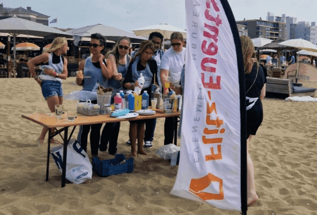 Lachende deelnemers genieten van een vrolijk verf-gooi evenement tijdens een bedrijfsuitje in Scheveningen