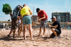 Collega’s strijden in teamverband tijdens uitdagende Robinson Crusoe Scheveningen proeven vol denk- en doe-opdrachten op het strand.